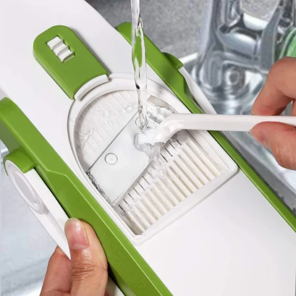 Easy-to-clean adjustable vegetable slicer being rinsed under water with cleaning brush