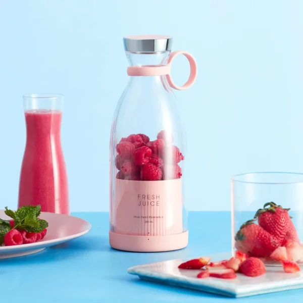Portable electric bottle juicer with raspberries, fresh juice, and strawberries on a blue background