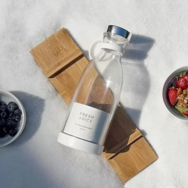 White portable electric blender bottle juicer outdoors with fresh blueberries and granola on snow