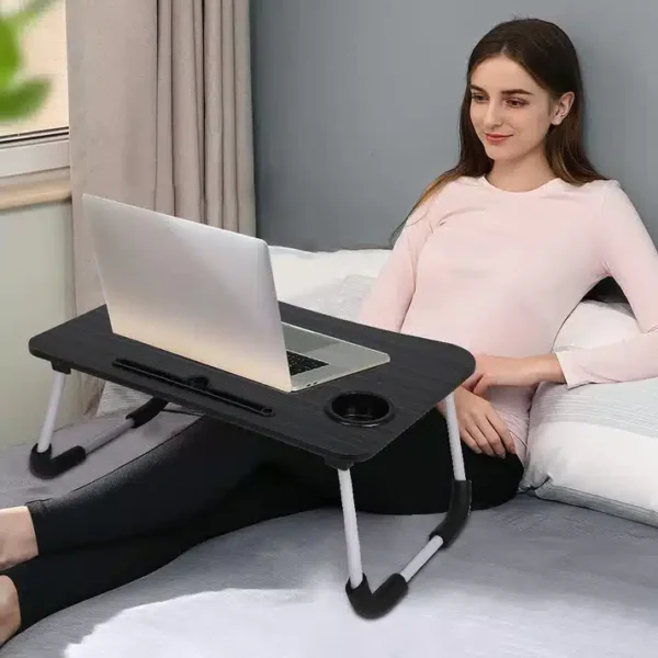Woman using a foldable laptop table on bed, ideal for work or study from home