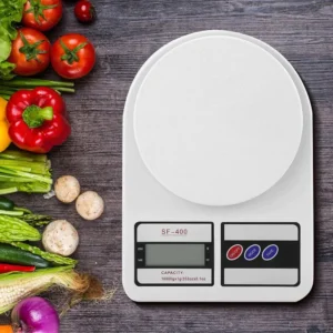 Digital kitchen scale with vegetables arranged on wooden surface