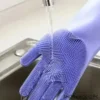 Silicone dishwashing glove with scrubbing bristles being rinsed under running water in kitchen sink