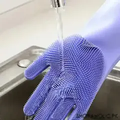 Silicone dishwashing glove with scrubbing bristles being rinsed under running water in kitchen sink
